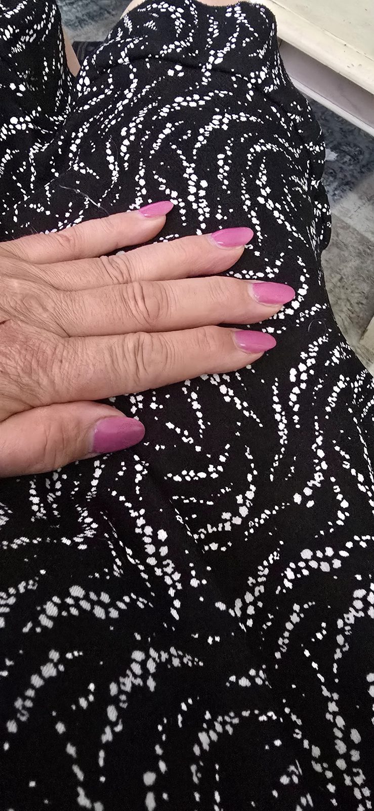 Roze nagels tegen een zwart-wit gestipte jurk
